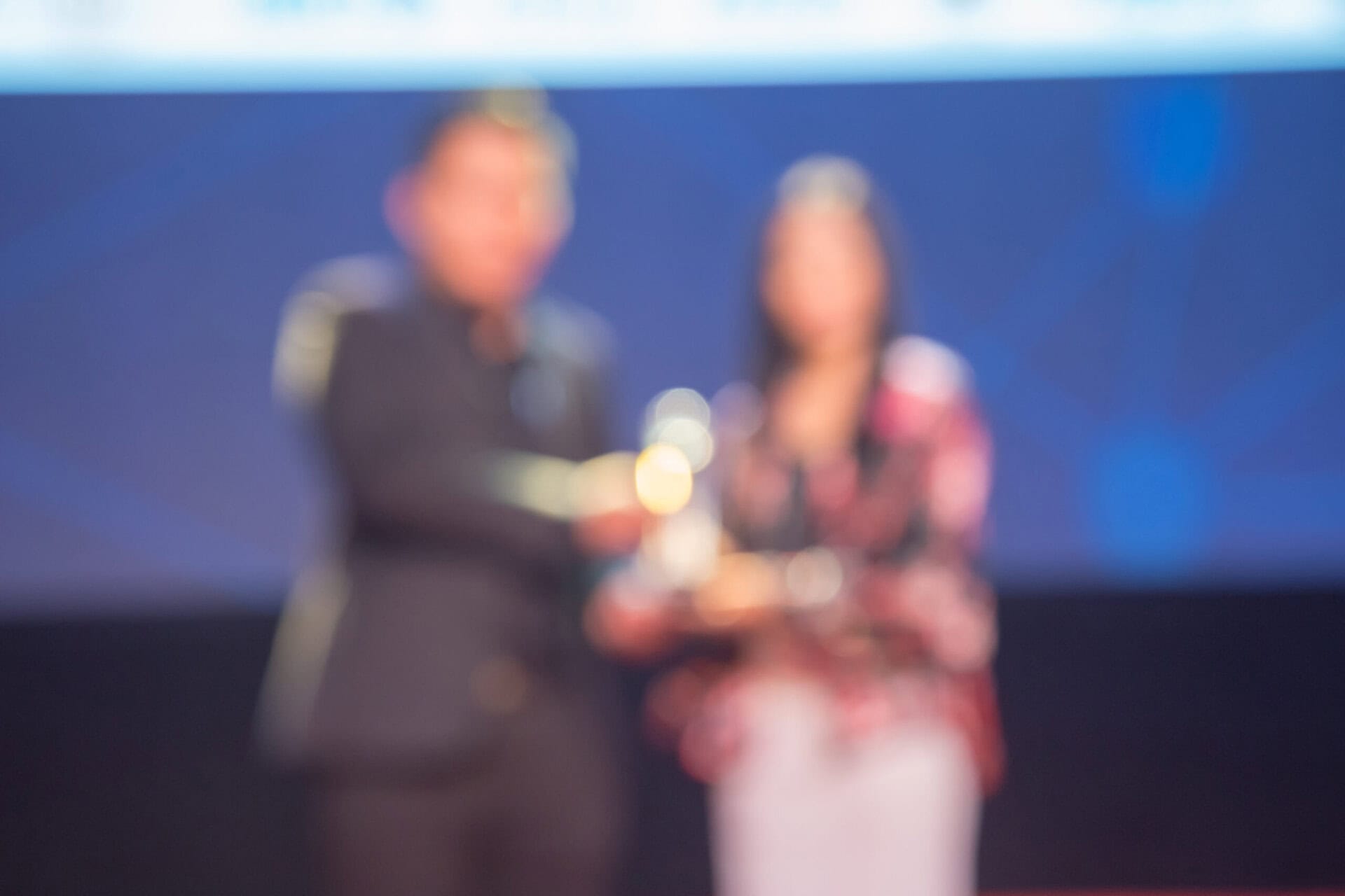 Award event featuring two individuals presenting or accepting a trophy, emphasizing awards and recognition.