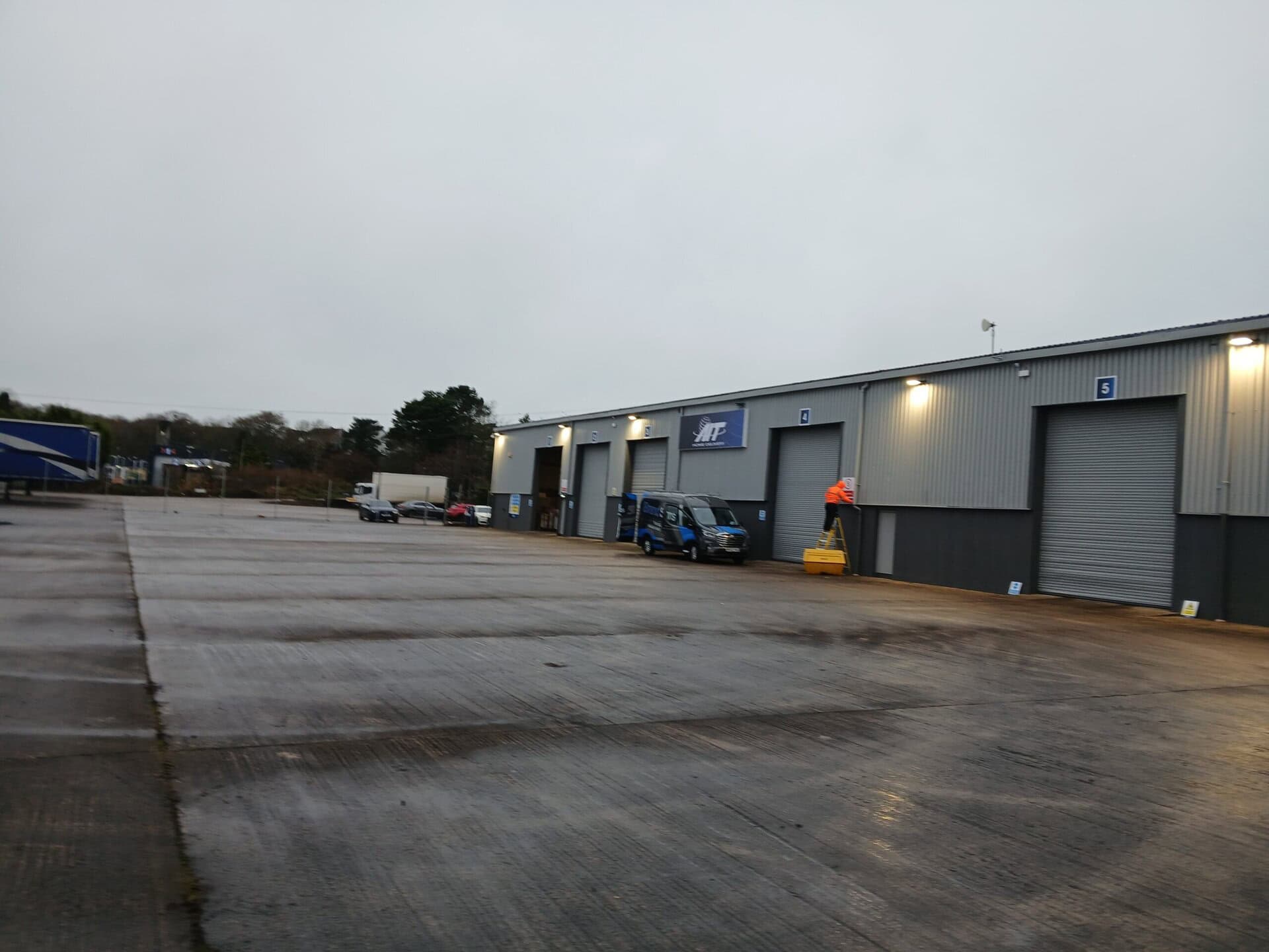 Warehouse exterior with loading bays and staff performing maintenance work.