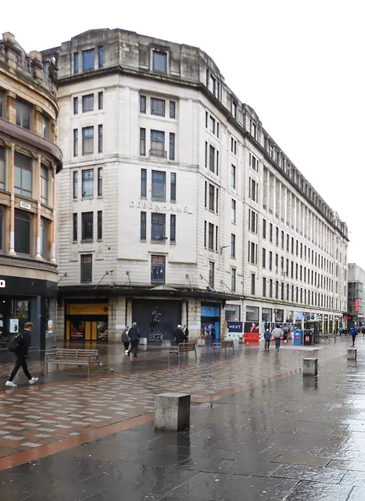 City street view of a large historic building with shops and pedestrians.